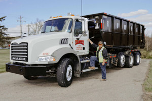 Rumpke Driver Next To Truck With Roll Off Dumpster For Waste Pickup